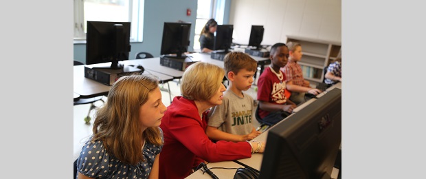 Photo of Molly Spearman with children sitting at a computer.